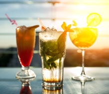 3 unique cocktails on a table with the sunsetting behind them