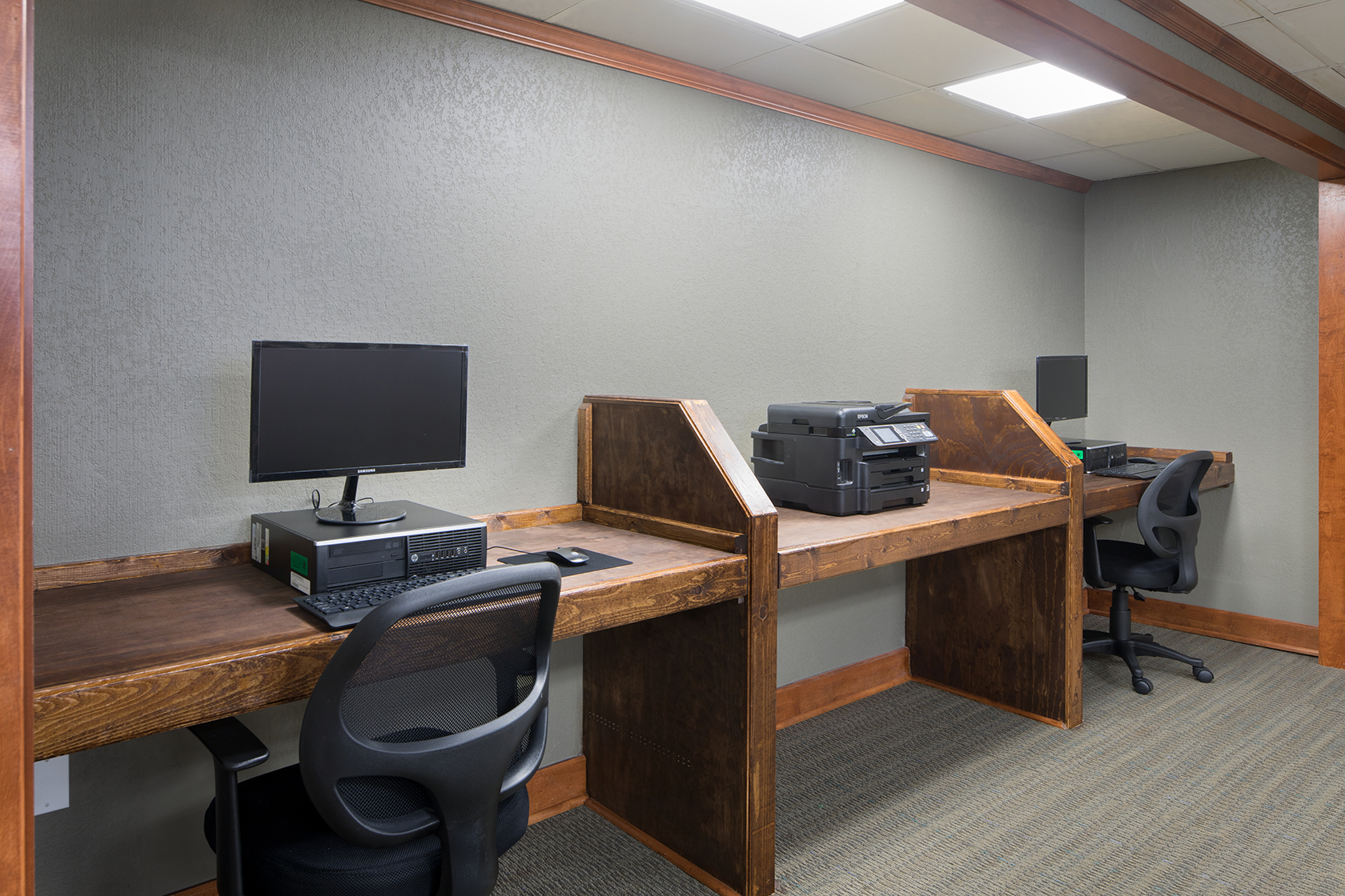 Business center with wooden work desk areas, computers and a printer