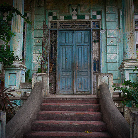 Blue door and cement steps of abandoned haunted house