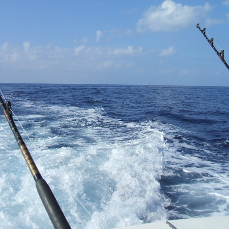 Two Fishing Reels on the ocean with white wake on blue water