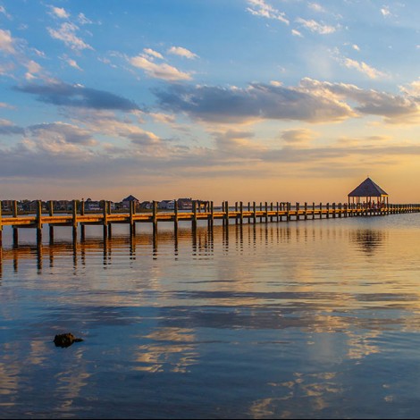 long beach and shoreline with pier during sunset