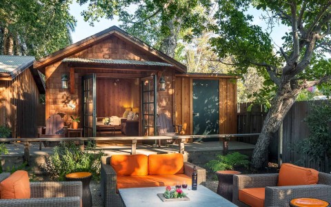 a wooden cabin with an outdoor seating area with orange cushions