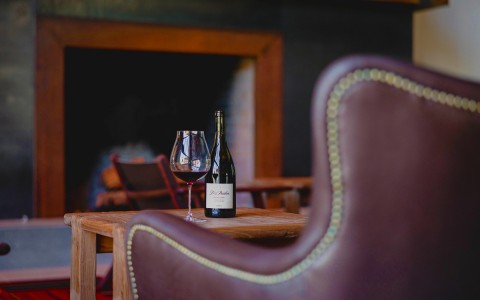 leather chair and wine bottle next to wine glass on table