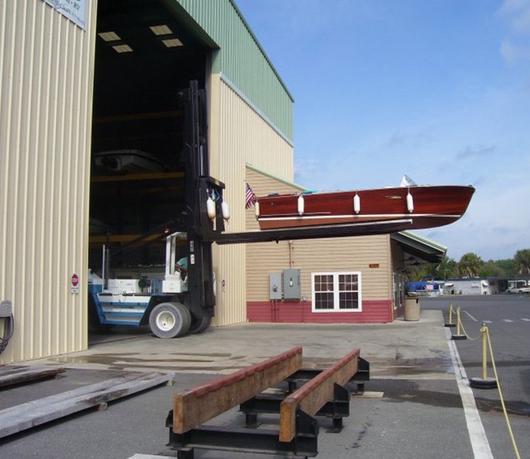 a forklift carrying a boat up into the dry storage building