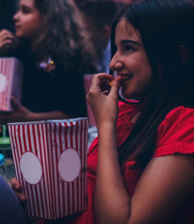 a girl eating popcorn watching a movie