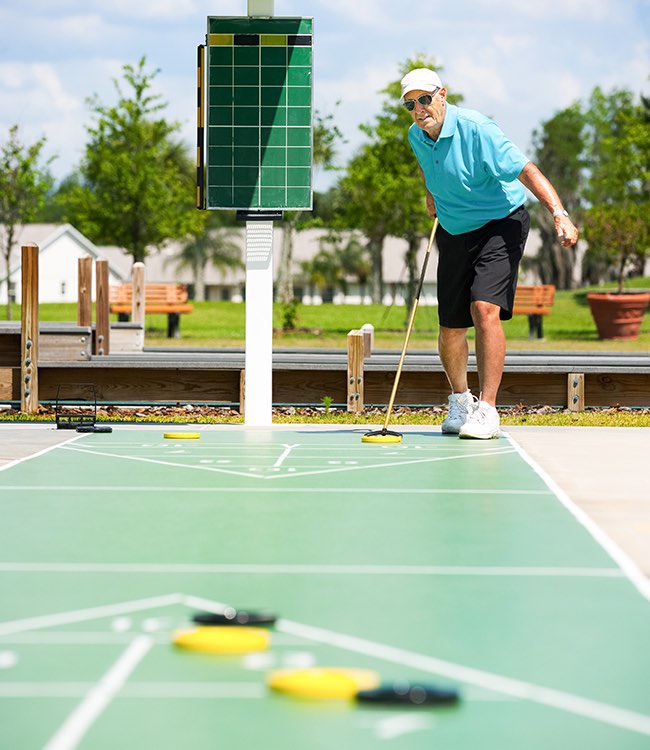 an older man in a light blue shirt playing shuffleboard