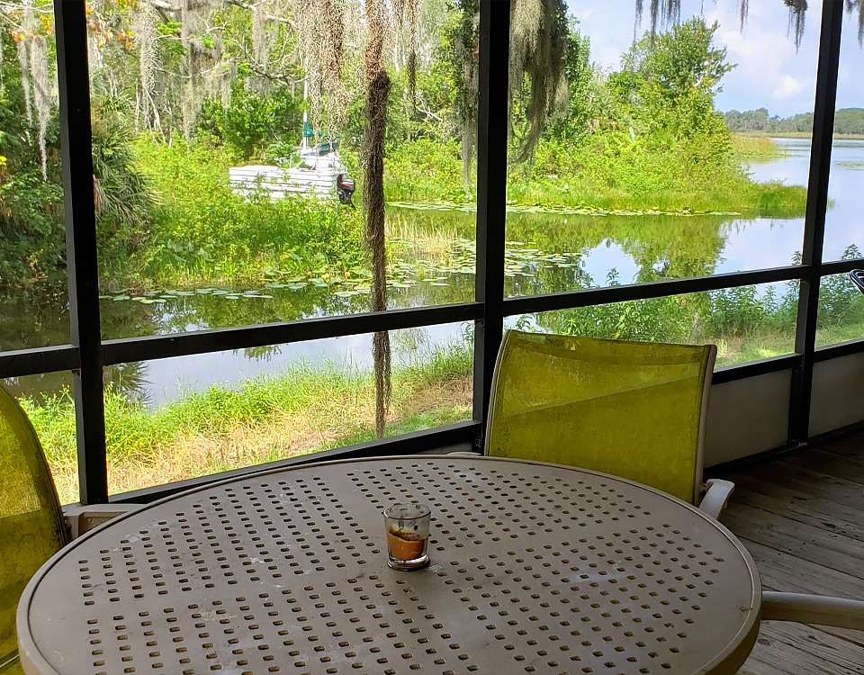 screened in porch with a table overlooking the water