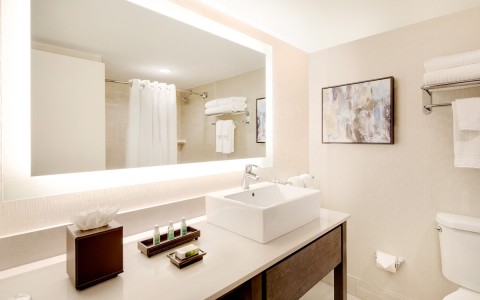 white bathroom with large mirror that has lights behind it