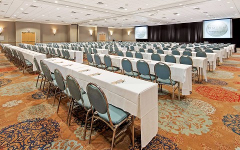 long white tables and blue chairs setup in a conference space