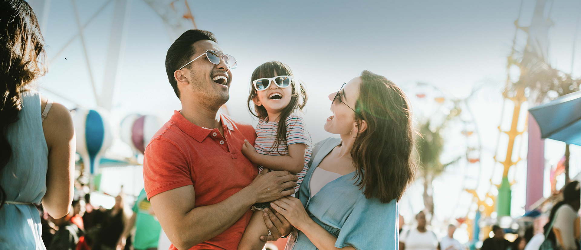family with sunglasses smiling in an amusement park