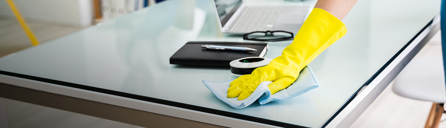 person with yellow glove wiping down table