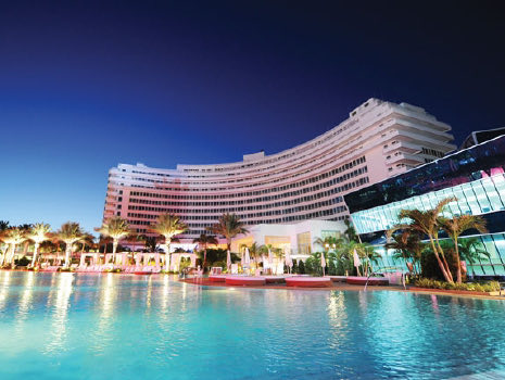 Front view of a large hotel and a big pool at night