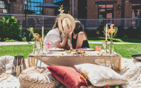 couple on picnic kissing behind hat