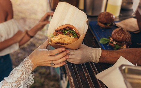 women picking up a burger from a food truck