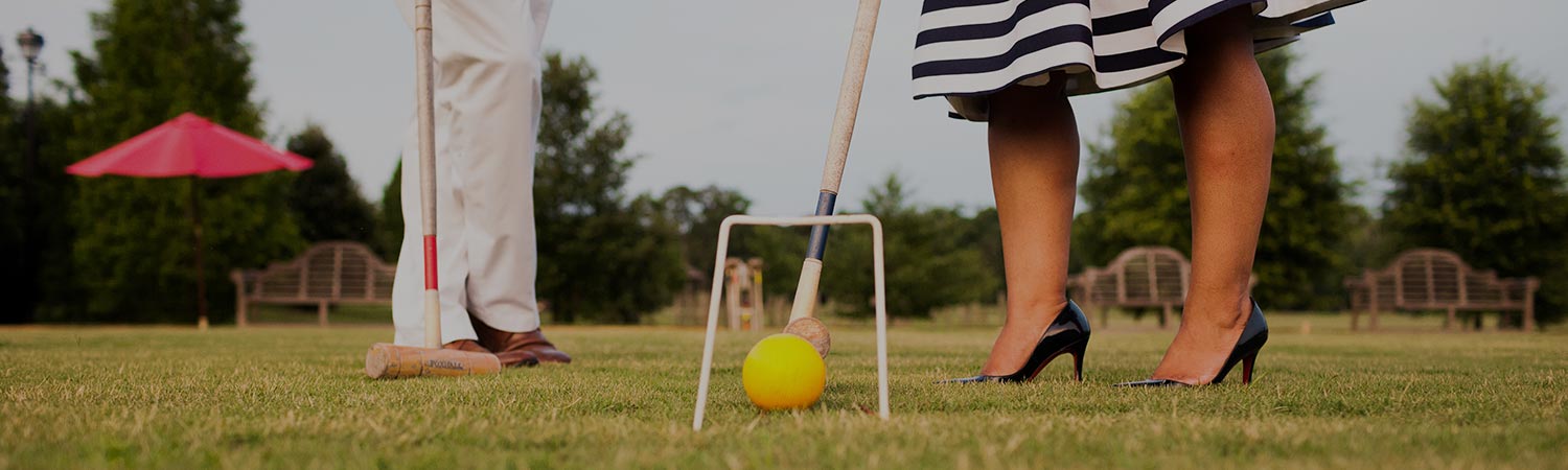 Close up of woman with heels on playing croquet next to man