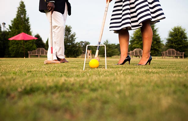 Close up of woman with heels on playing croquet next to man
