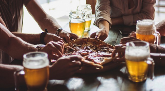 Group of friends splitting pizza and beer