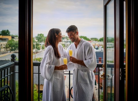 couple drinking mimosas in their bath robes on the hotel balcony 