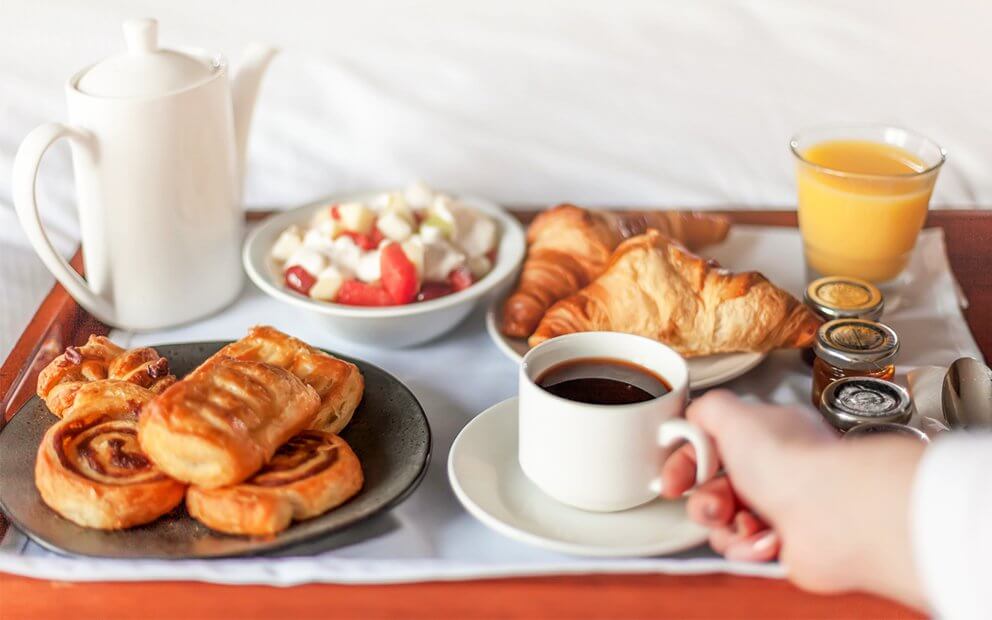 woman holding coffee cup on a tray of breakfast foods