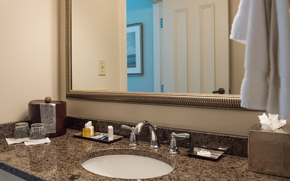 Bathroom granite vanity with sink, toiletry samples & large gold framed mirror
