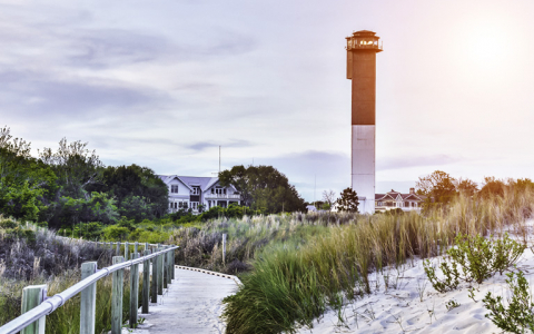 lighthouse next to a house overlooking a sand dune