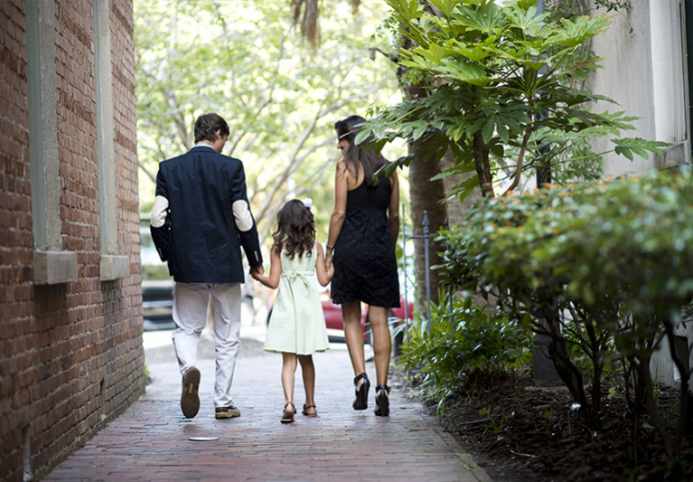 Couple with daughter walking down brick path