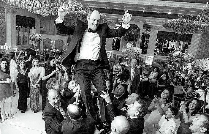 groom being lifted up on a chair on the dancefloor