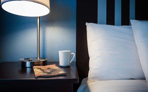 bed next to nightstand with magazine and coffee cup