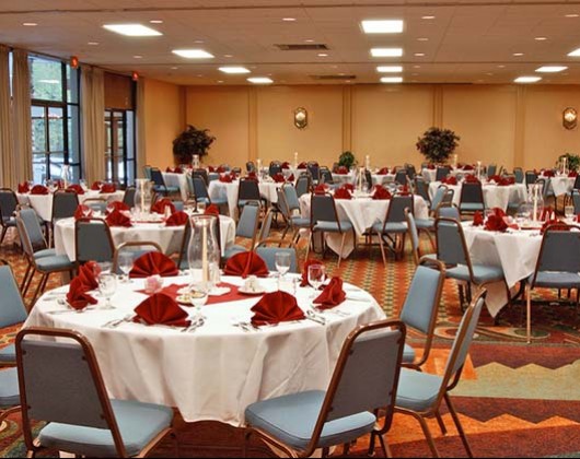 glenstonelodge azalea room with multiple white round tables and blue chairs with red decor napkins