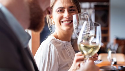 woman smiling to a guy while they are making a toast with white wine