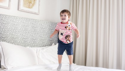little boy jumping on bed