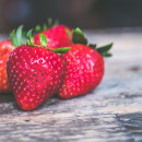 Four ripe strawberries on a wooden table