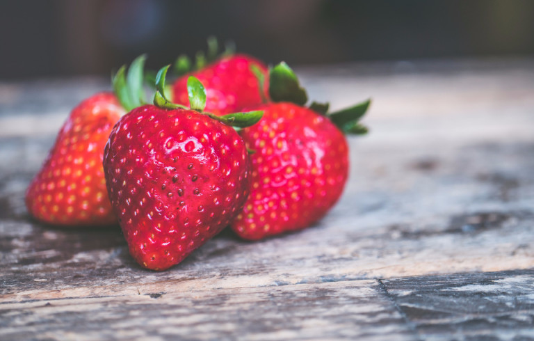 Four ripe strawberries on a wooden table
