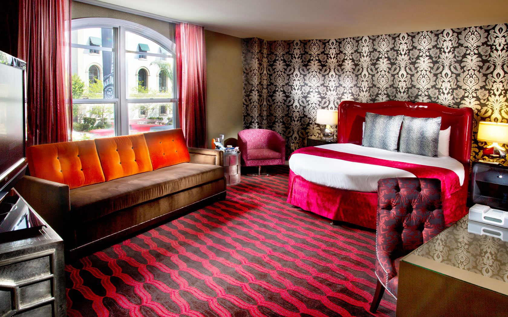 West Los Angeles Hotels Stay Near La Round Bed With Red Bedding Curtains And Pattern Carpet