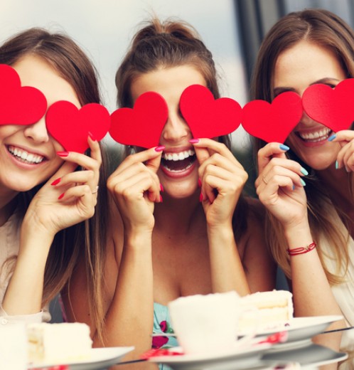 Three girlfriends holding hearts in cafe