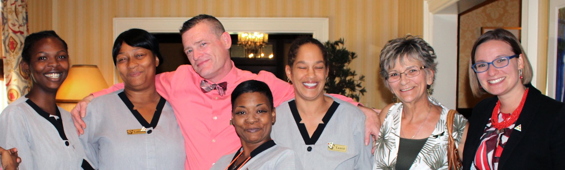 A group of workers with their arms around each other smiling for a picture