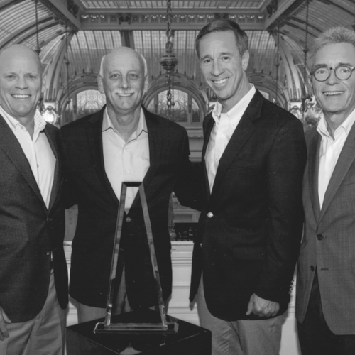 four businessmen standing behind a trophy