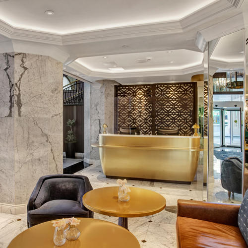 lobby with gold desk, gold tables and seating next to the tables 