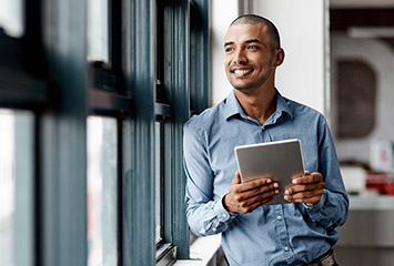 a business man looking out a window holding a tablet