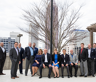 group of professionals sitting and standing outside in front of a tree