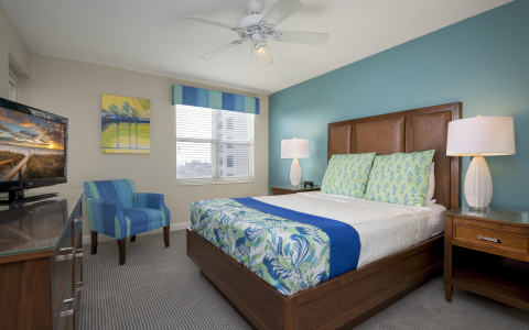 Room with king bed, blue accent decor, wooden furniture & window