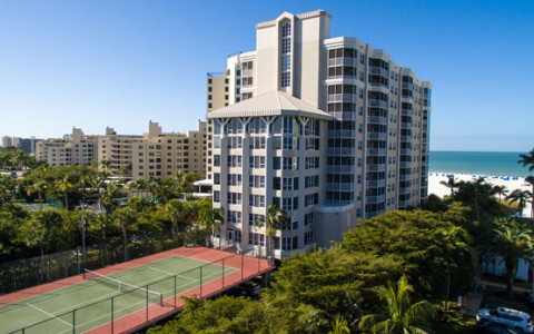 Video thumbnail of hotel building with tennis court on one side & beach on the other 