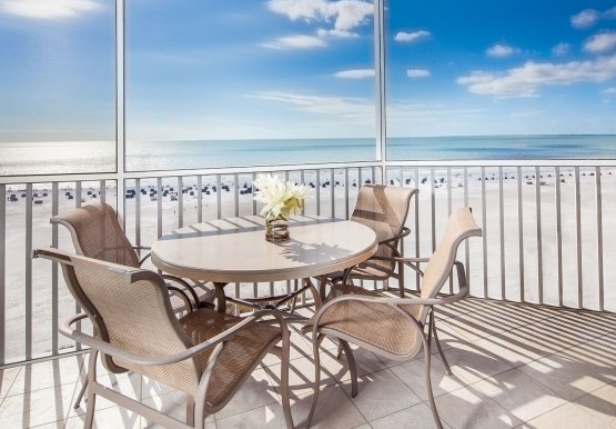 Table with chairs on balcony overlooking ocean 