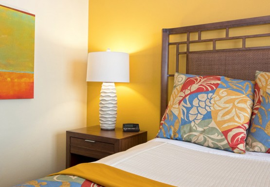 Close up of bed with tropical print comforter & wooden nightstand