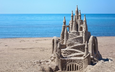 Big & detailed sand castle beside the ocean water