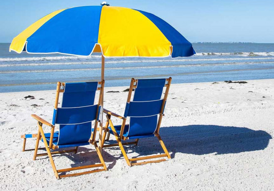 two chairs and a blue and yellow umbrella on the beach shore