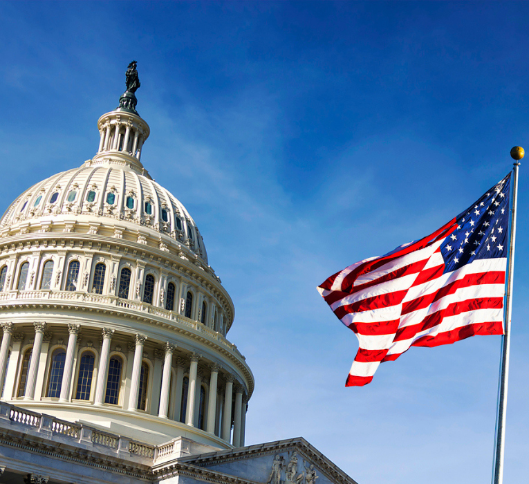 An americamflag on a flag post next to the capitol building
