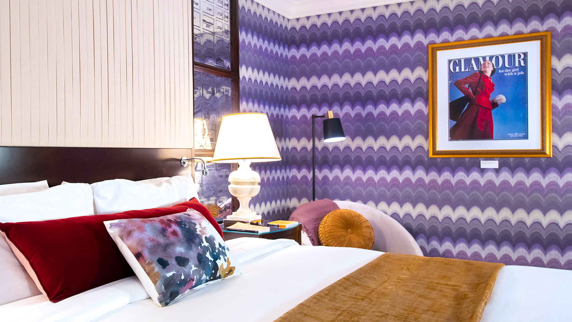 room with purple pattern on the wall and a queen bed 