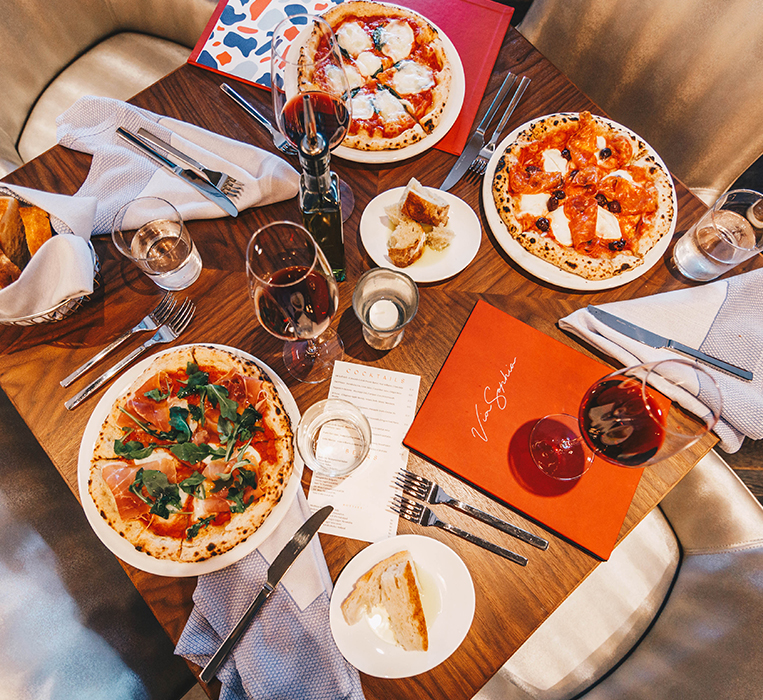 above view of a table with pizzas and glasses of wine