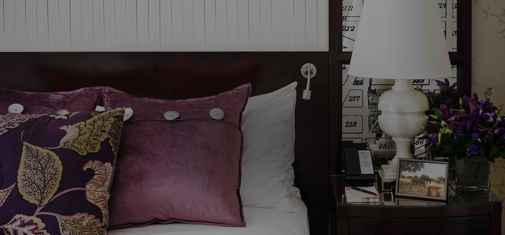 close up of bed with purple pillows and a night stand